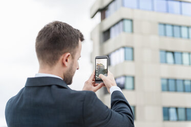 Geschäftsmann, der ein Handyfoto von einem Bürogebäude macht - DIGF000654