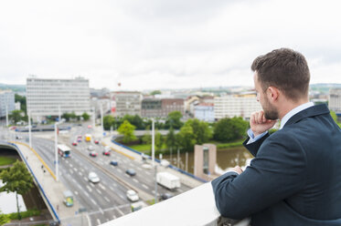 Businessman on roof terrace looking on city - DIGF000656