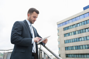 Businessman looking at digital tablet in front of office building - DIGF000658