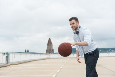 Businessman playing basketball outdoors - DIGF000673