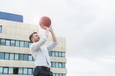 Businessman playing basketball outdoors - DIGF000674