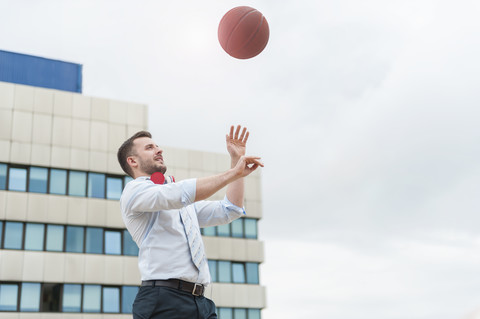 Geschäftsmann spielt Basketball im Freien, lizenzfreies Stockfoto