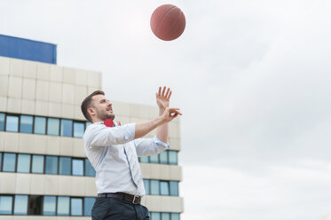 Businessman playing basketball outdoors - DIGF000675