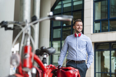 Smiling young man wearing headphones outdoors - DIGF000689