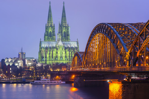 Deutschland, Köln, Blick auf den beleuchteten Kölner Dom mit der Hohenzollernbrücke im Vordergund, lizenzfreies Stockfoto