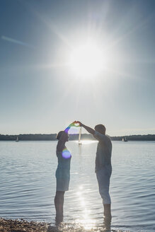 Paar am Cospudener See, das mit den Händen ein Herz gegen die Sonne formt - MJF001975