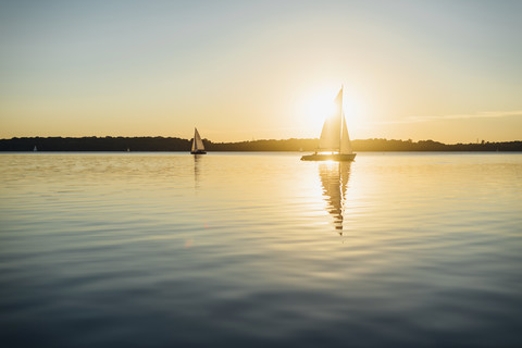 Segelboot auf dem Cospudener See bei Sonnenuntergang, lizenzfreies Stockfoto