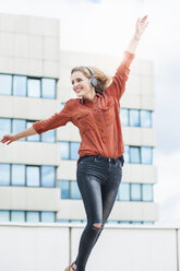 Dancing woman with arms outstretched listening music with headphones - DIGF000728