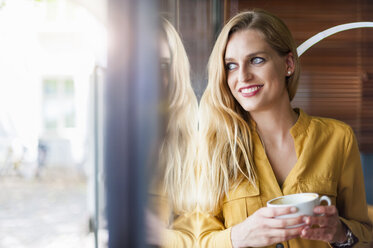 Portrait of smiling woman in a coffee shop looking through window - DIGF000766