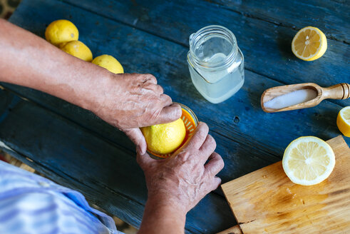 Close-up of hands squeezing lemons to make lemonade - KIJF000584