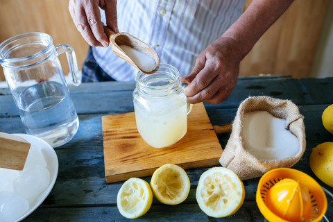 Nahaufnahme der Hände, Mann gibt Zucker in Limonade, lizenzfreies Stockfoto