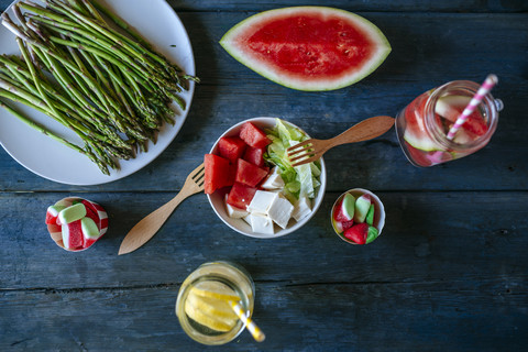 Tisch mit Salat, Wassermelone, Limonade, Spargel und Süßigkeiten, lizenzfreies Stockfoto