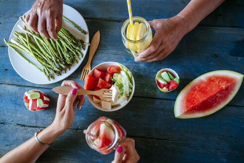 Nahaufnahme von Händen, die Salat, Wassermelone, Limonade, Spargel und Bonbons essen - KIJF000595