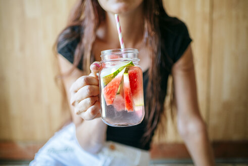 Nahaufnahme einer Frau, die ein Glas Wassermelone hält - KIJF000597