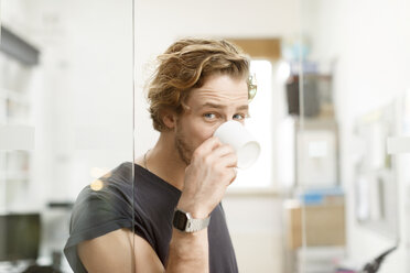 Junger Mann trinkt Kaffee im Büro - PESF000207