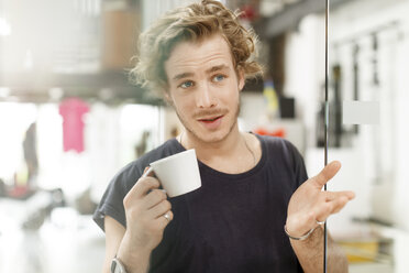Young man drinking coffee in office - PESF000208