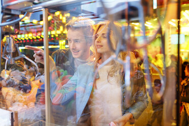 Junges Paar auf dem Jahrmarkt betrachtet die Preise im Fenster - PES000232