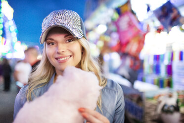 Young woman at fun fair eating candy floss - PES000242