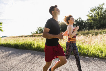 Young couple running on country road - UUF008086