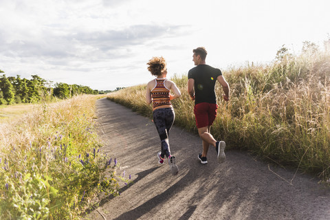 Junges Paar läuft auf einem Feldweg, lizenzfreies Stockfoto