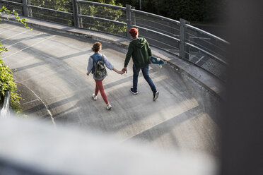 Junges Paar mit Skateboard geht Hand in Hand im Parkhaus - UUF008100