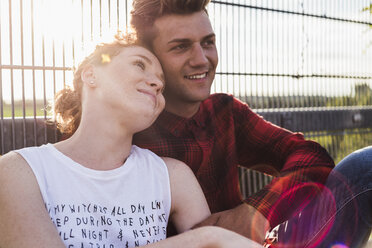 Smiling young couple at a fence - UUF008110