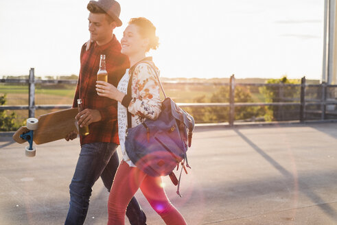 Junges Paar mit Bierflaschen und Skateboard bei Sonnenuntergang - UUF008132
