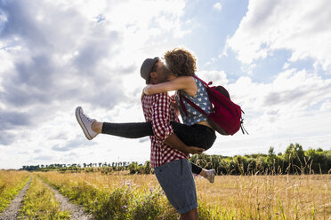 Young couple kissing on field path - UUF008153