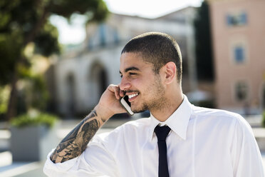 Lächelnder junger Geschäftsmann beim Telefonieren mit Smartphone - GIOF001255