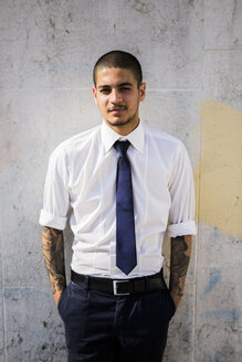 Porträt eines jungen Geschäftsmannes mit Tattoos auf den Unterarmen - GIOF001285