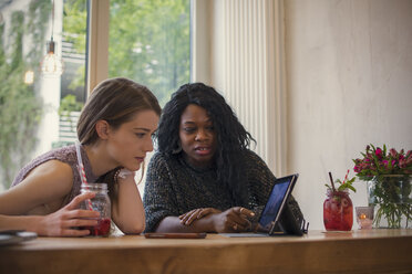 Zwei junge Frauen benutzen ein digitales Tablet in einem Cafe - ONF000932