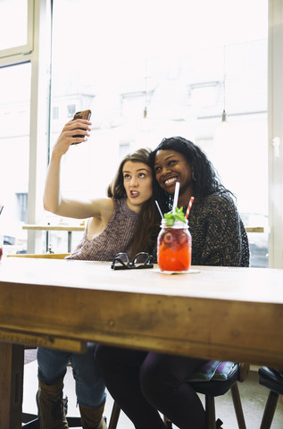 Zwei junge Frauen machen ein Selfie in einem Cafe, lizenzfreies Stockfoto