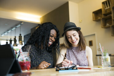 Zwei Freunde benutzen ein digitales Tablet in einem Cafe - ONF000983