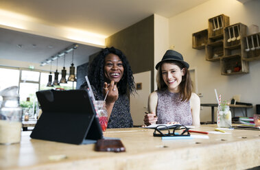 Zwei Freunde benutzen ein digitales Tablet in einem Cafe - ONF000985