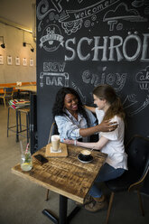 Zwei Freunde treffen sich in einem Café und umarmen sich - ONF001003