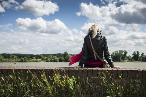 Woman sitting on wall, Rhine riverside stock photo