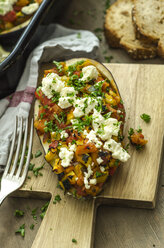 Filled aubergine with bell pepper, tomato, courgette, sheep cheese and parsley on chopping board - ODF001413