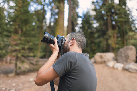 Junger Tourist, der im Wald fotografiert, lizenzfreies Stockfoto