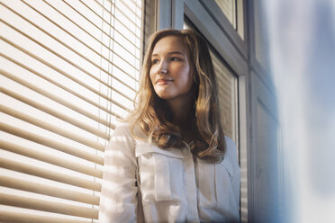 Young woman looking through window - GCF000202