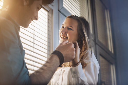 Junger Mann und Frau vor einem Fenster, flirtend - GCF000205