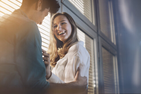 Junger Mann und Frau vor einem Fenster, flirtend - GCF000206