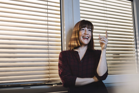 Porträt einer lachenden Frau am Fenster, lizenzfreies Stockfoto