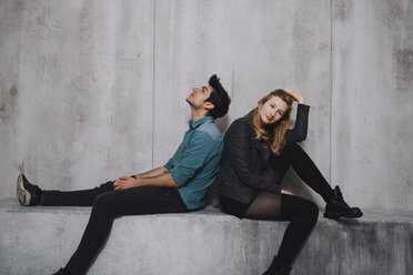 Young couple sitting in front of concrete wall - GCF000211