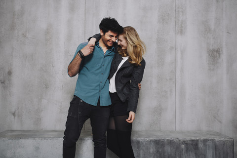 Young couple embracing in front of concrete wall stock photo