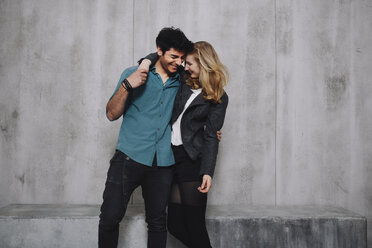 Young couple embracing in front of concrete wall - GCF000217