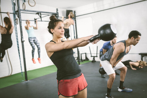 Menschen im Fitnessstudio, die mit Kettle Bells trainieren - MAD000988