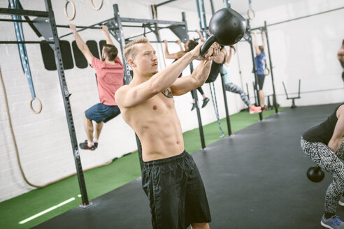 Menschen im Fitnessstudio, die mit Kettle Bells trainieren - MAD000989