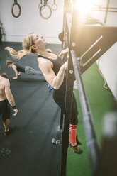 Frau im Fitnessstudio macht Klimmzüge - MAD000990