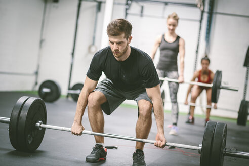 Menschen im Fitnessstudio, die Gewichte heben - MAD000995