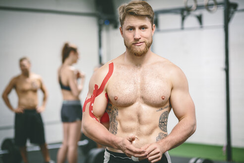 Junger muskulöser Mann im Fitnessstudio mit bandagierter Schulter - MAD000997